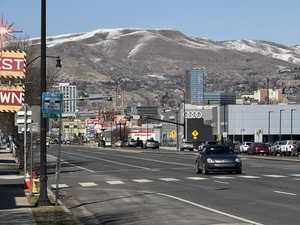 View of street featuring traffic lights, street lighting, traffic signs, a mountain view, and sidewalks