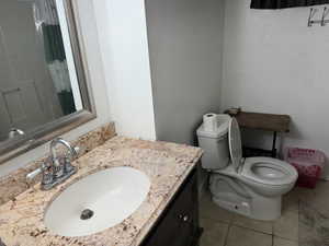 Full bathroom featuring toilet, curtained shower, tile patterned flooring, and vanity