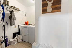 Clothes washing area with washer and dryer and light hardwood / wood-style floors