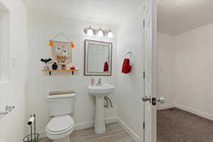 Bathroom with a textured ceiling, toilet, and hardwood / wood-style flooring