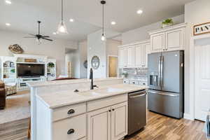 Kitchen with appliances with stainless steel finishes, hanging light fixtures, an island with sink, white cabinets, and sink