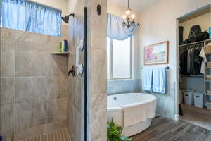 Bathroom with a chandelier, independent shower and bath, and tile walls