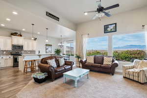 Living room with a mountain view, light hardwood / wood-style floors, and ceiling fan with notable chandelier