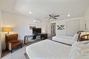 Bedroom featuring a wall mounted AC, light carpet, ceiling fan, and a closet