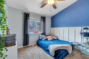 Carpeted bedroom featuring ceiling fan and vaulted ceiling