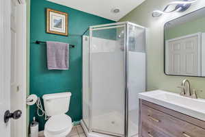 Bathroom with tile patterned floors, toilet, a shower with door, and vanity