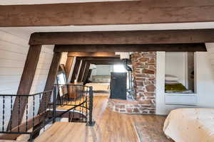 Bedroom featuring light hardwood / wood-style flooring, wooden walls, and beamed ceiling