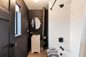 Bathroom featuring tiled shower / bath combo, vanity, and hardwood / wood-style floors