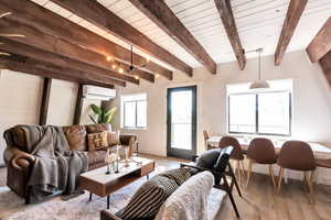 Living room with a wall mounted air conditioner, wooden ceiling, beam ceiling, and light hardwood / wood-style flooring