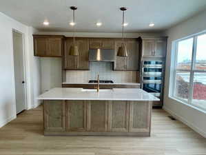 Gourmet kitchen features gorgeous maple cabinets, 36-inch gas cooktop with stainless steel hood, quartz countertops, farmhouse sink, built-in wall oven, walk-in pantry, and an island nearly 8 feet long.