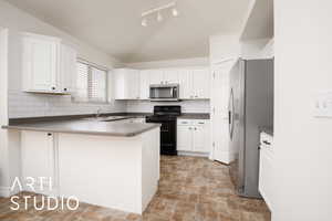 Kitchen with stainless steel appliances, white cabinetry, backsplash, and kitchen peninsula