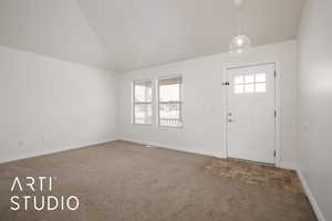 Entryway featuring lofted ceiling and carpet flooring