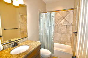 Full bathroom featuring shower / bathtub combination with curtain, vanity, and toilet