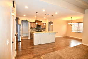 Kitchen featuring hanging light fixtures, stainless steel appliances, dark hardwood / wood-style flooring, backsplash, and a breakfast bar area