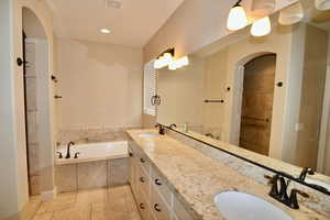 Bathroom with tile patterned floors, vanity, and tiled tub