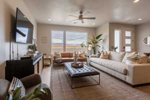 Living room featuring dark hardwood / wood-style flooring, ceiling fan, and a textured ceiling