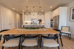 Kitchen with stainless steel appliances, decorative light fixtures, sink, backsplash, and white cabinets