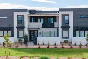 Contemporary house featuring a balcony and a front yard