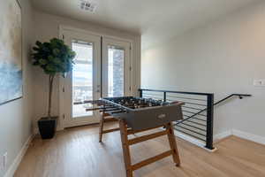 Rec room with light hardwood / wood-style floors and french doors