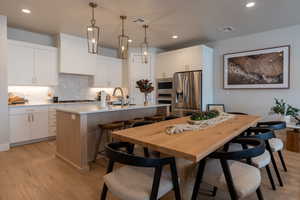 Kitchen with white cabinets, a kitchen island with sink, and stainless steel appliances