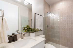 Bathroom with vanity, a shower with shower door, and toilet