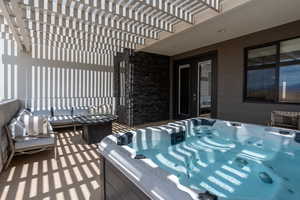 View of patio with a hot tub, an outdoor living space, and a pergola