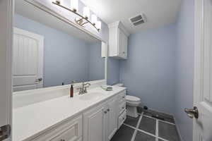 Bathroom with a textured ceiling, toilet, vanity, and tile patterned flooring