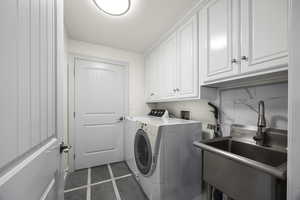 Washroom featuring cabinets, dark tile patterned floors, sink, and independent washer and dryer