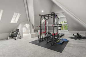 Workout room with carpet floors and lofted ceiling with skylight