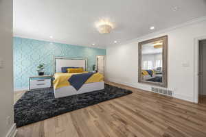 Bedroom with light wood-type flooring, crown molding, and a textured ceiling