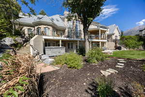 Rear view of property with a hot tub, a mountain view, and a balcony