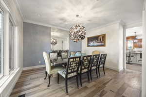 Dining room with ornamental molding, an inviting chandelier, and light hardwood / wood-style flooring