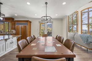 Dining space with a textured ceiling, dark hardwood / wood-style floors, ornamental molding, and a chandelier