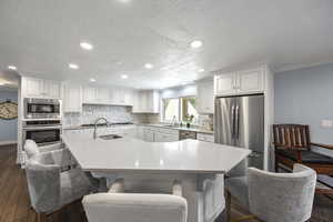 Kitchen with sink, stainless steel appliances, a kitchen island with sink, and a breakfast bar area