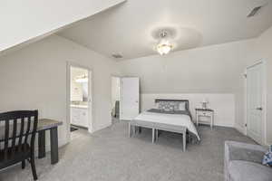 Bedroom with vaulted ceiling, ensuite bath, and light colored carpet