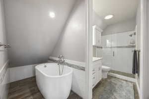 Full bathroom featuring lofted ceiling, vanity, separate shower and tub, toilet, and hardwood / wood-style flooring