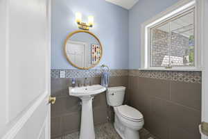 Bathroom featuring tile walls, sink, and toilet