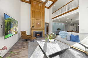 Living room featuring light hardwood / wood-style floors, a tiled fireplace, and a high ceiling