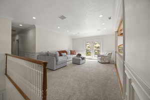 Carpeted living room with french doors, crown molding, and a textured ceiling