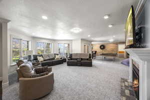 Carpeted living room featuring a wealth of natural light, a textured ceiling, wood walls, and ornamental molding