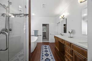 Bathroom featuring tile walls, ornamental molding, vanity, and independent shower and bath