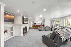 Living room with carpet, ornamental molding, and a textured ceiling