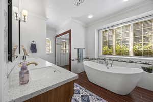 Bathroom featuring tile walls, ornamental molding, vanity, and a washtub