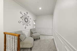 Living area with ornamental molding and light carpet