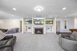 Carpeted living room with a brick fireplace, crown molding, and a textured ceiling