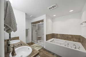 Bathroom with shower with separate bathtub, vanity, and a textured ceiling