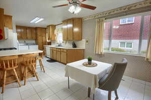 Kitchen with washer and dryer, sink, dishwasher, light tile patterned floors, and a kitchen bar