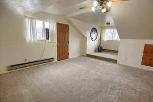 Additional living space featuring light colored carpet, vaulted ceiling, and a baseboard heating unit