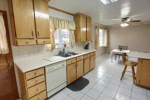 Kitchen with sink, white dishwasher, ceiling fan, light tile patterned flooring, and decorative backsplash