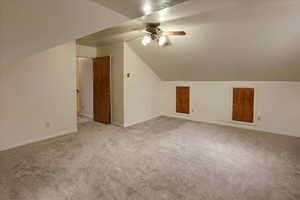 Additional living space with ceiling fan, vaulted ceiling, and light carpet